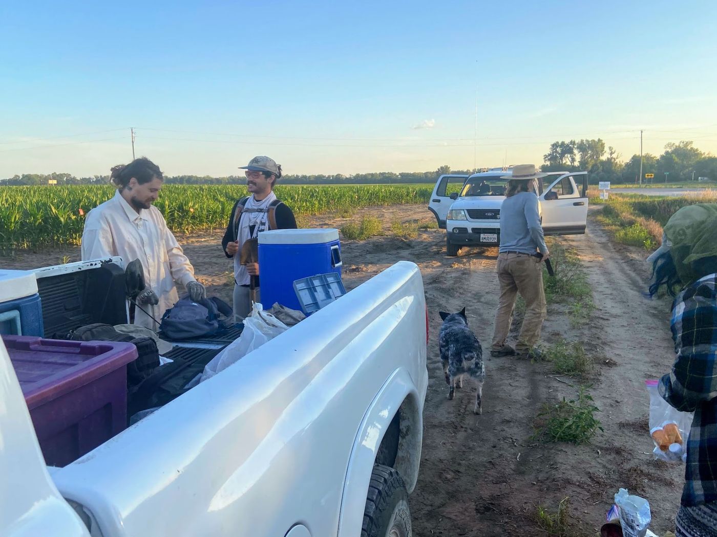 The crew gathered around a pickup tailgate at dusk
